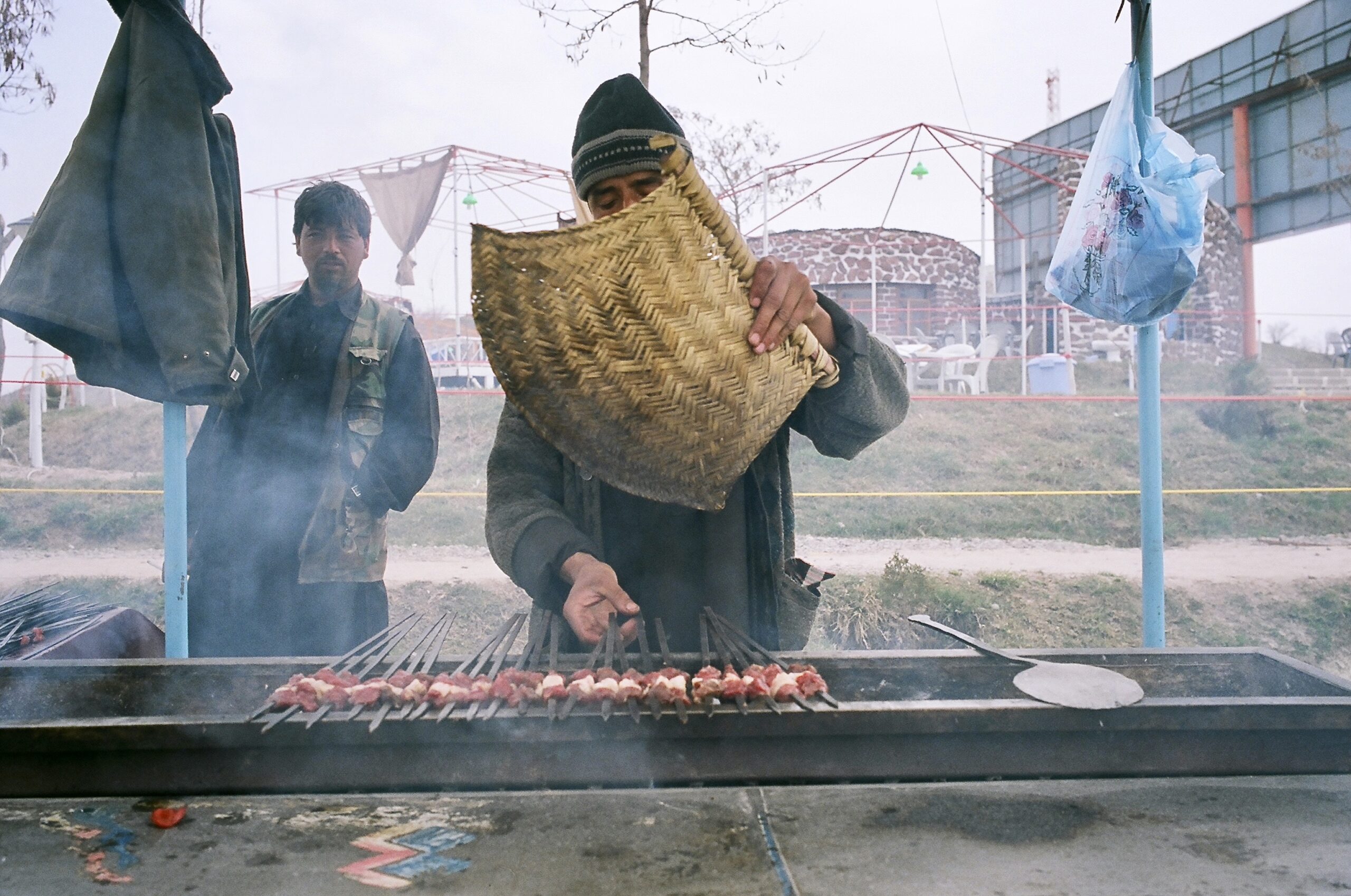 Afghan men cook kebabs on a grill at Bande Qargha.